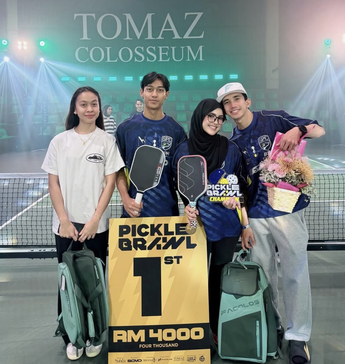 Four attendees posing with the Picklebrawl first-prize board and trophy